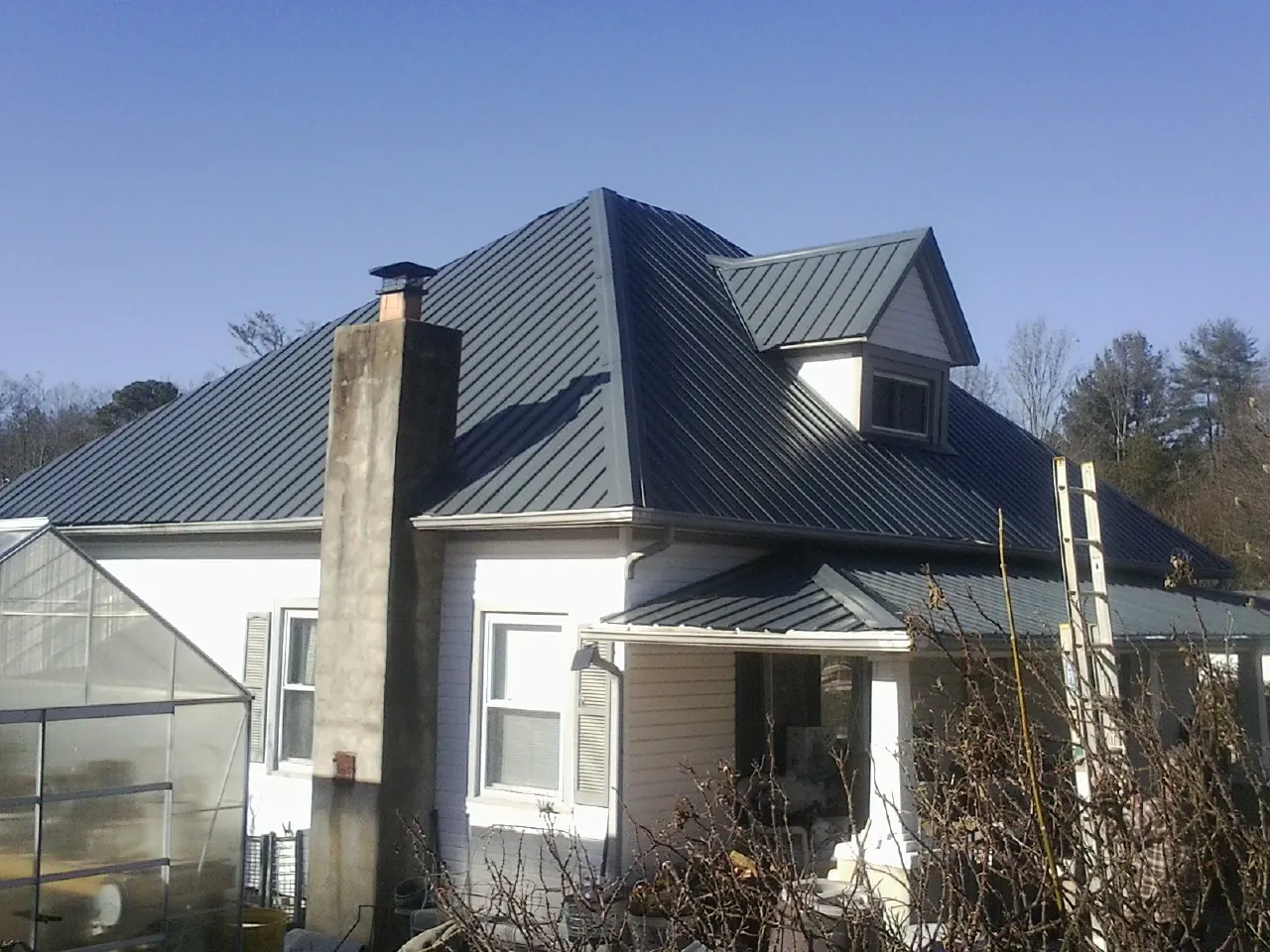 Dark blue standing seam metal roof on a white farmhouse with dormer — Slate & Tile Roof Repair by Roofing Brothers in Monroe Township