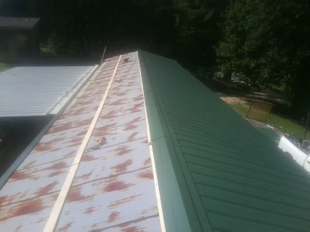 Old rusted panels beside newly installed green metal roofing — Wind Damage Roof Repair by Roofing Brothers in Monroe Township