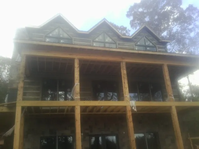 Dormers and porch framing on a large log home under construction — Roof Coating work by our crew in Monroe Township