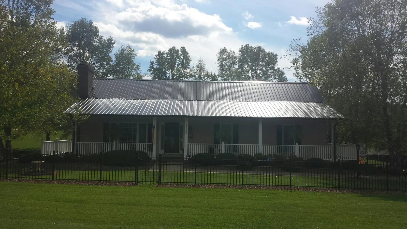 Gray metal roof on a brick ranch with a full width front porch — Gutter Guard Installation work by our crew in Monroe Township