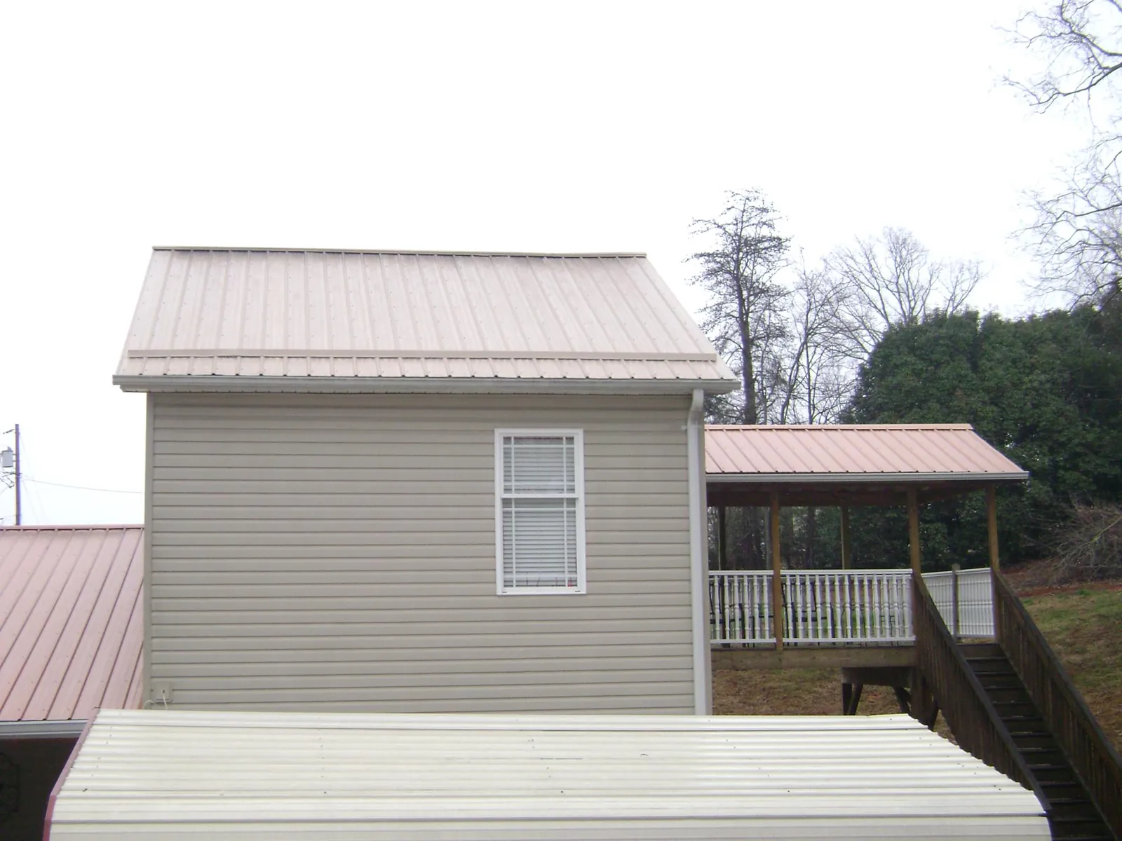 Tan metal roofs on a two story addition and attached porch, from a Roof Replacement job in Monroe Township