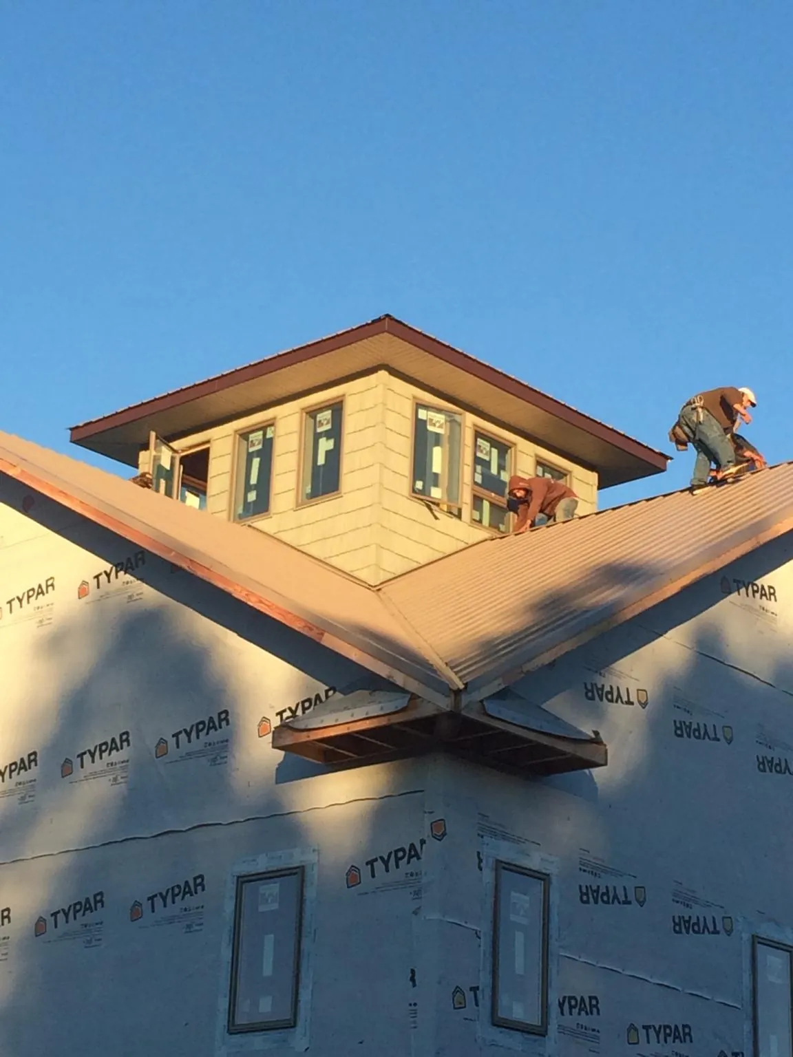 Roofers working around a rooftop cupola on a new metal roof at sunset — Roof Waterproofing in Monroe Township by Roofing Brothers